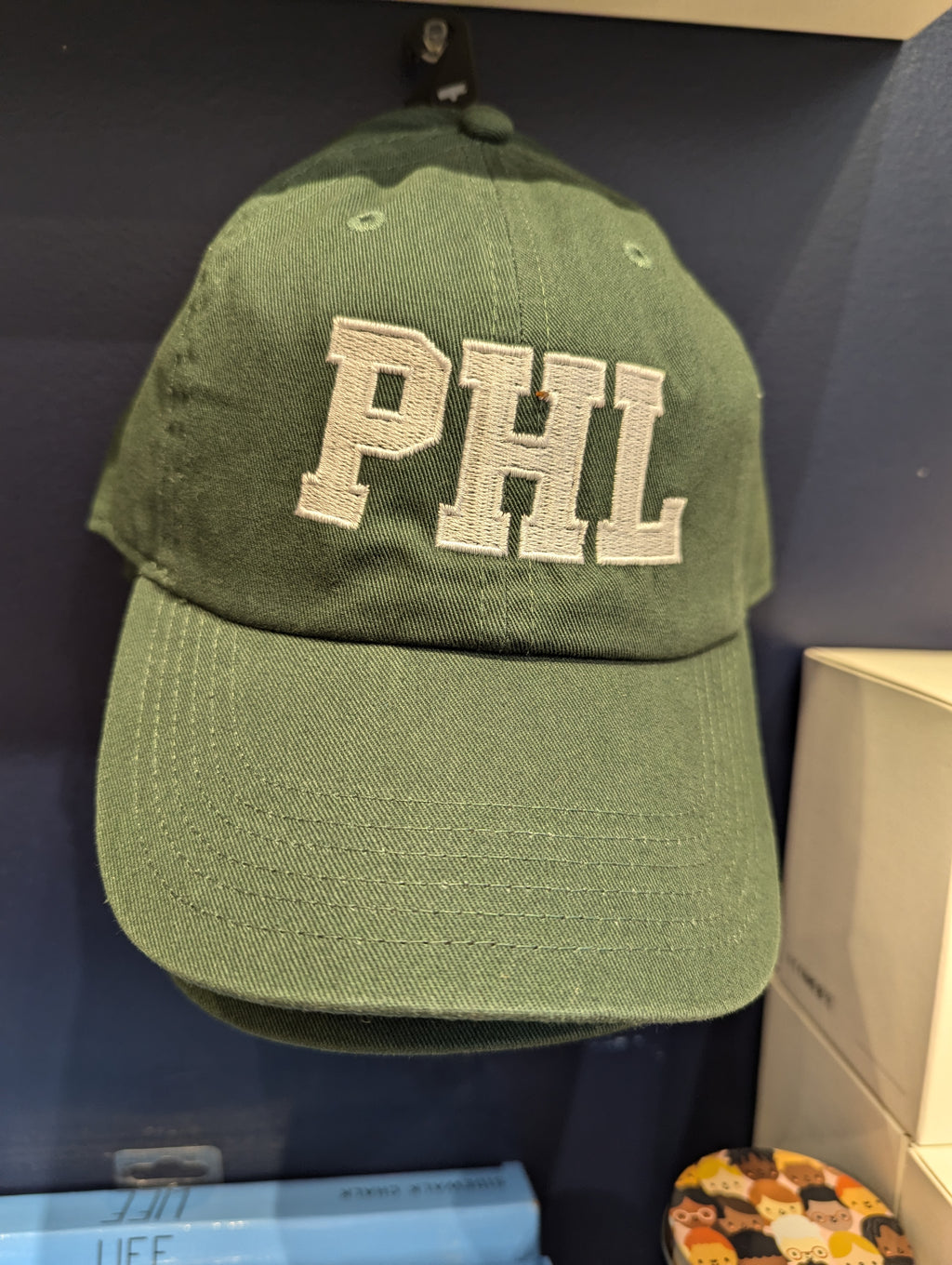 A green baseball cap with 'PHL' embroidered on the front.